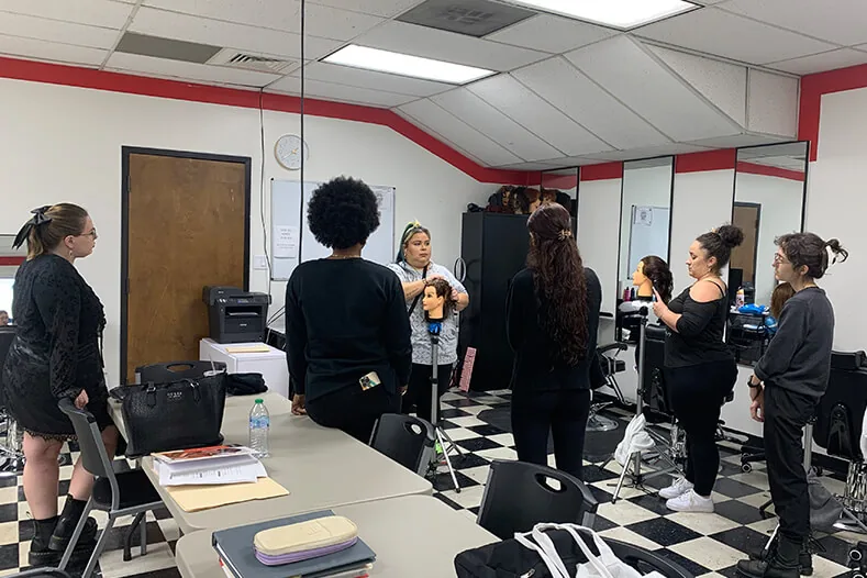 Cosmetology class watching an instructor work on a mannequin head at Hyphen in Winter Park, FL, near Ocoee