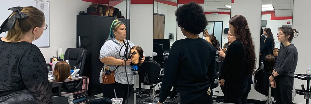 Cosmetology instructor demonstrating on a mannequin as students watch at Hyphen in Winter Park, FL, near Lake Mary