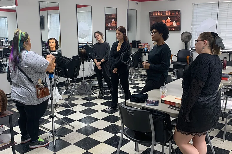 Cosmetology instructor demonstrating hair color on a mannequin for students