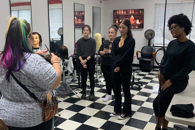 Cosmetology instructor showing students how to section hair on a mannequin at Hyphen in Winter Park, FL