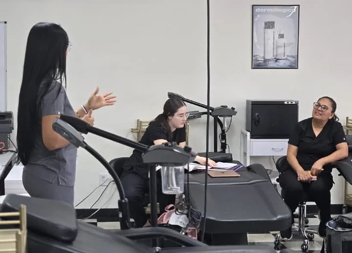 Esthetics instructor teaching students at the treatment beds at Hyphen Beauty + Massage School in Winter Park, FL