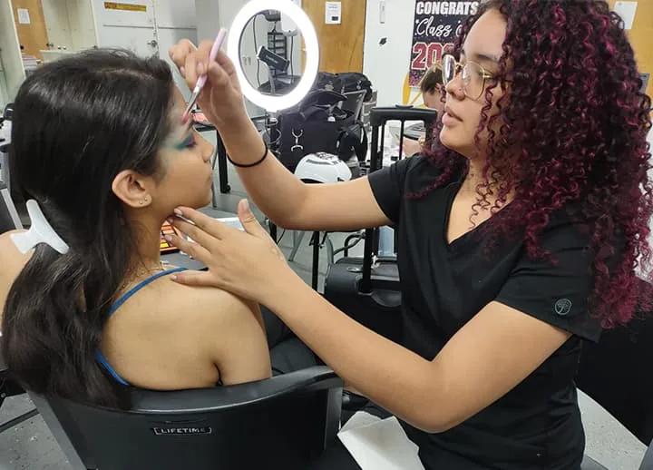 Makeup student applying eye makeup to a model in class at Hyphen Beauty + Massage School in Winter Park, FL