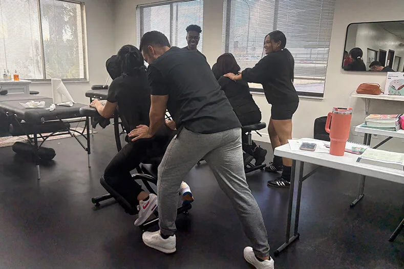 Small group of massage students practicing chair massage