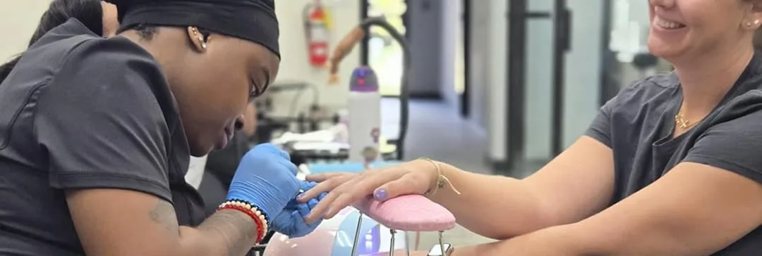 Nail tech student giving a client a manicure at Hyphen Beauty + Massage School in Winter Park, FL, near Oviedo